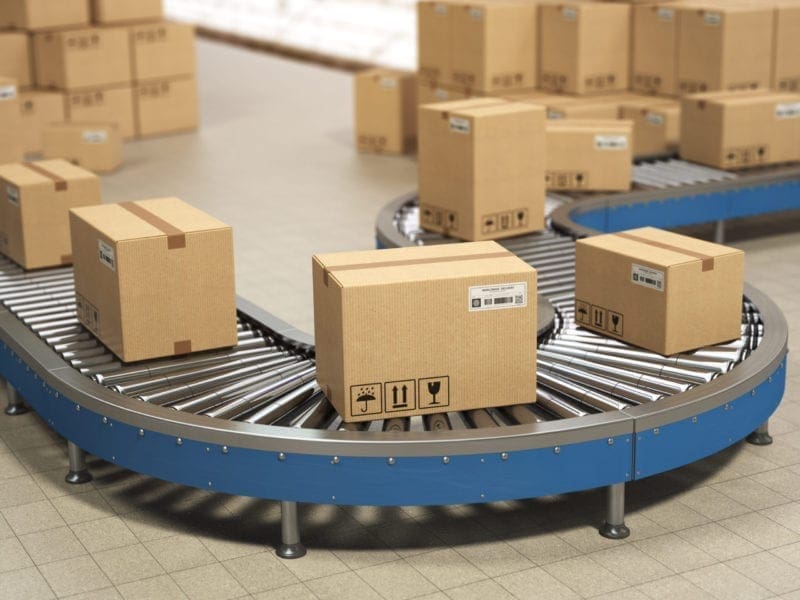 Cardboard boxes on conveyor roller in distribution warehouse, De Cardboard boxes on conveyor roller in distribution warehouse.